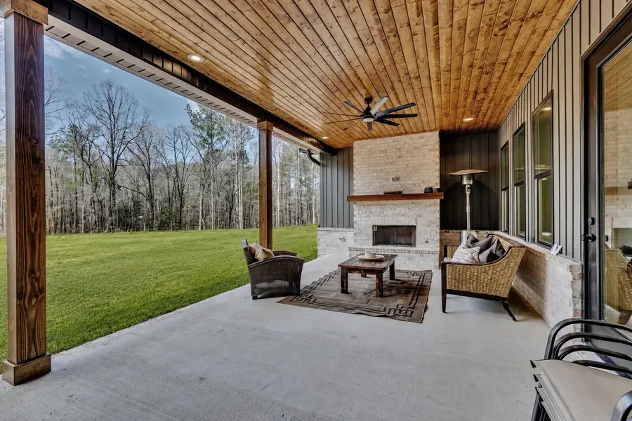 Covered outdoor living space with fireplace by Still Oak Homes