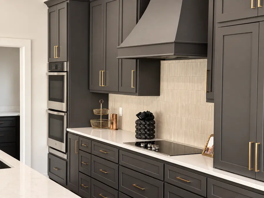 Custom charcoal kitchen cabinetry with brass hardware by Still Oak Homes